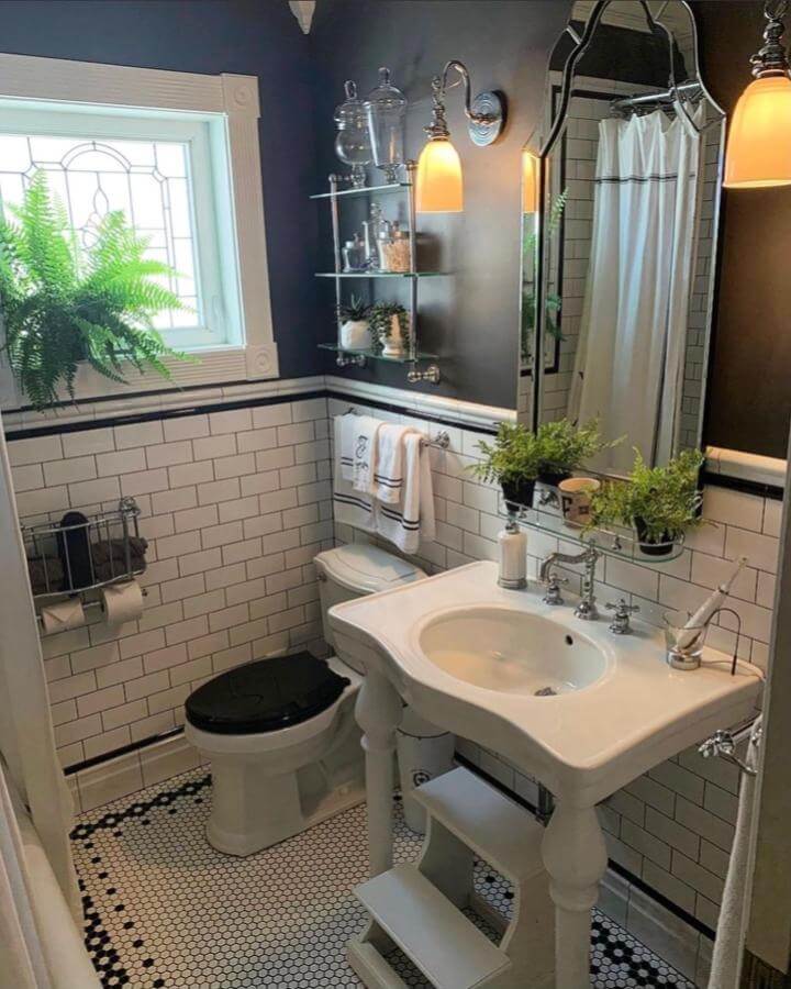 White subway tile bathroom with black trim and hex floor tiles from @samanthaefaella. Victorian bathroom ideas with vintage pedestal sink and elegant glass shelves.
