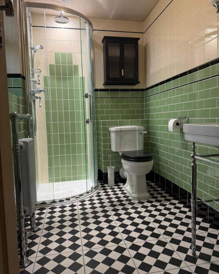 Black and white checkerboard floor tiles with green subway walls in victorian bathroom ideas by @victorian_period_floor_tiles. Elegant vintage style and modern glass shower enclosure.