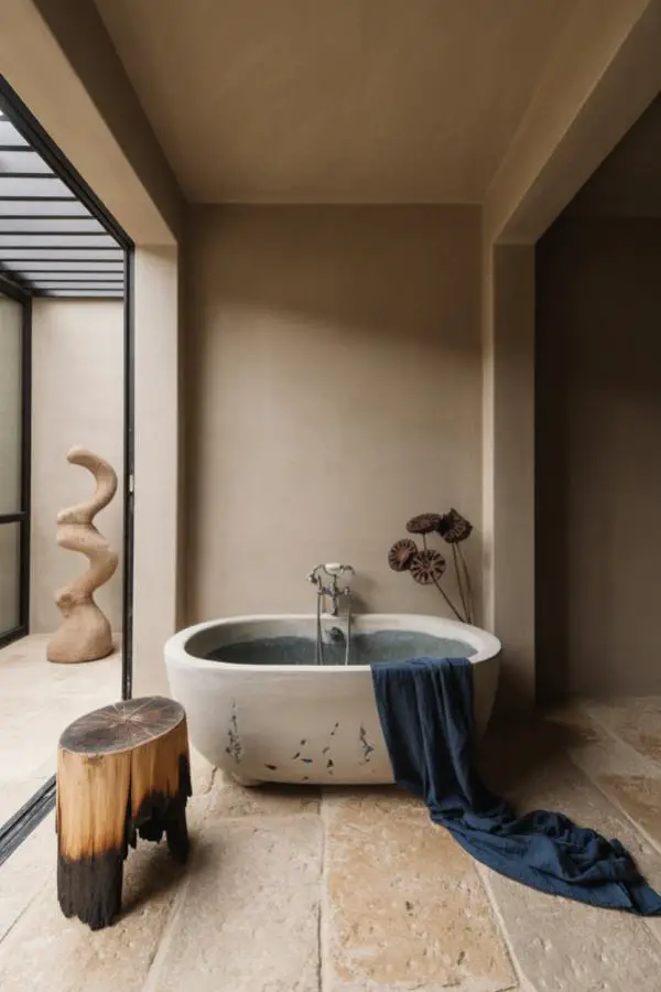 Natural wooden stump stool from @stiltje.se. Organic curves and raw edges beside white ceramic bathtub.