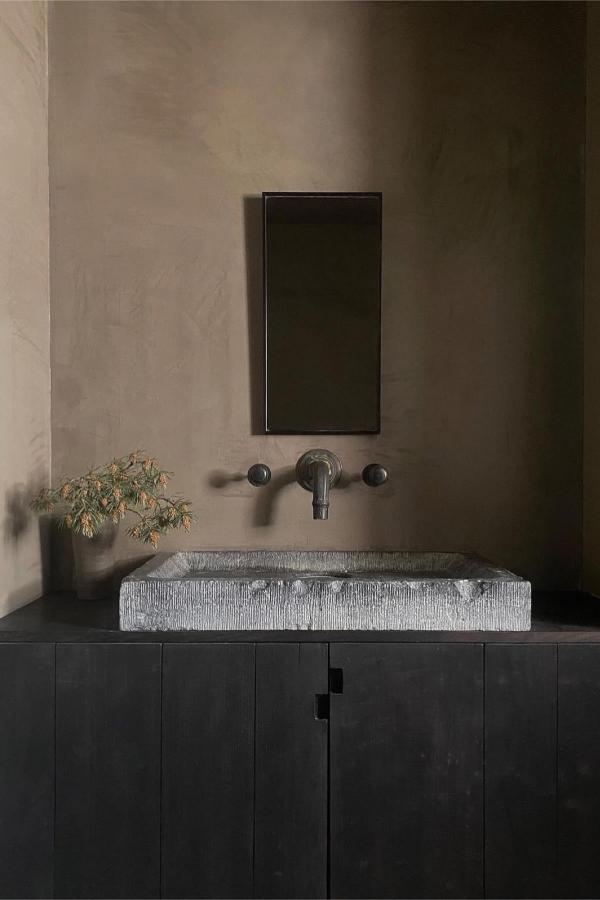 Textured grey stone vessel basin from @vado_uk. Dark vanity contrasts beautifully with natural weathered stone surface.