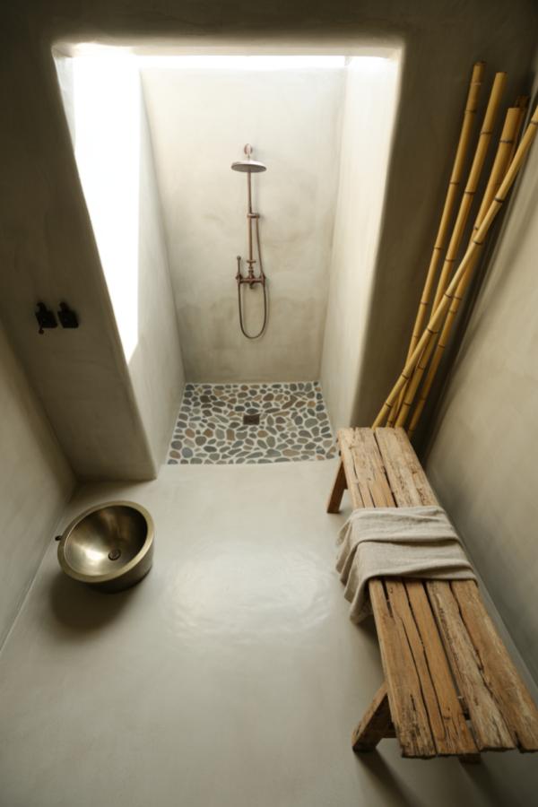 Minimal concrete bathroom featuring natural bamboo poles and weathered wood, perfect for wabi sabi bathroom ideas inspiration.