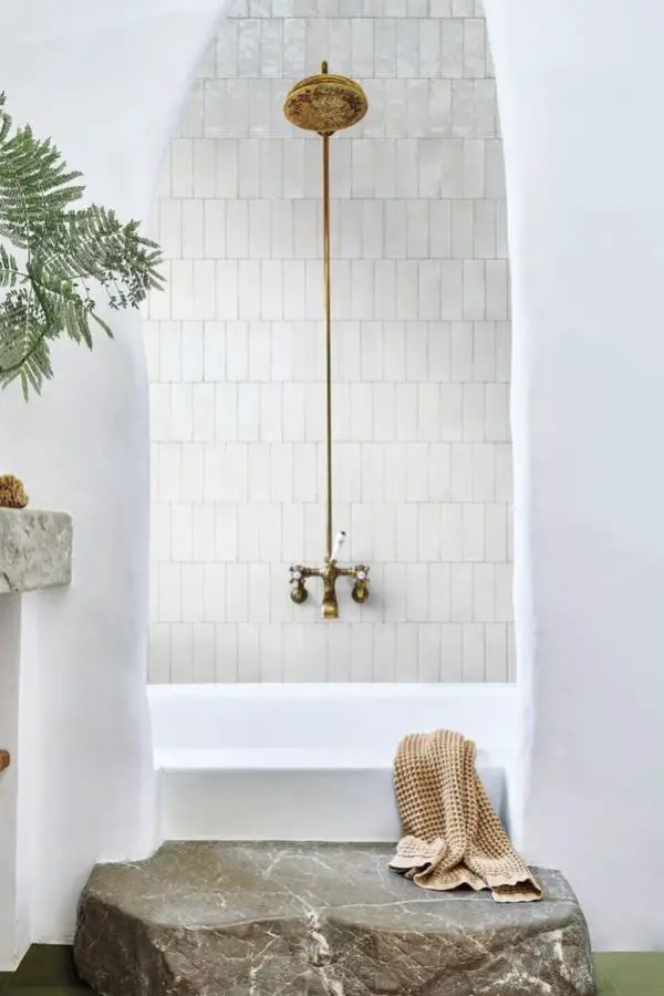 Aged brass shower fixtures from @arq.constanzadel displaying natural patina against white subway tile backdrop.