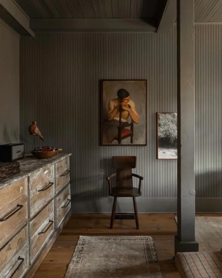 Distressed wooden dresser from @clementsdesign. Sage paneled walls showcase rustic vintage furniture with character.