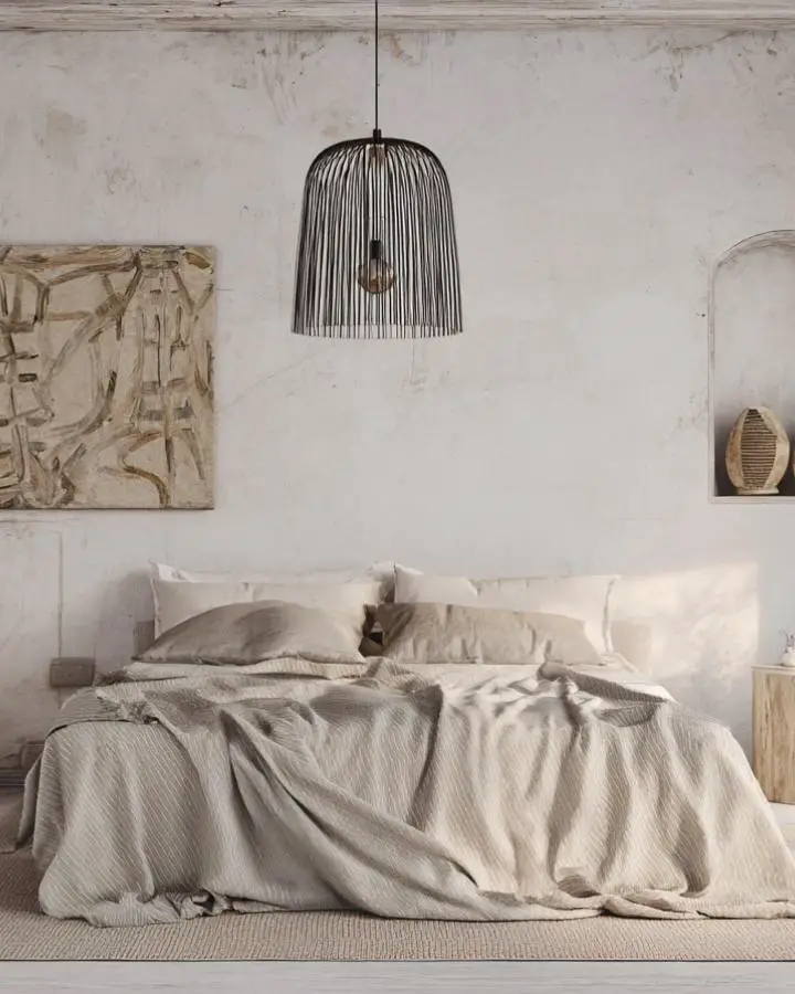 Neutral bedroom with rumpled linen bedding and natural textures. Weathered walls complement the unmade bed aesthetic.