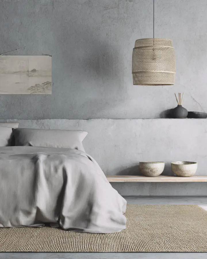 Textured concrete bedroom wall with natural woven pendant light and minimal decor elements.