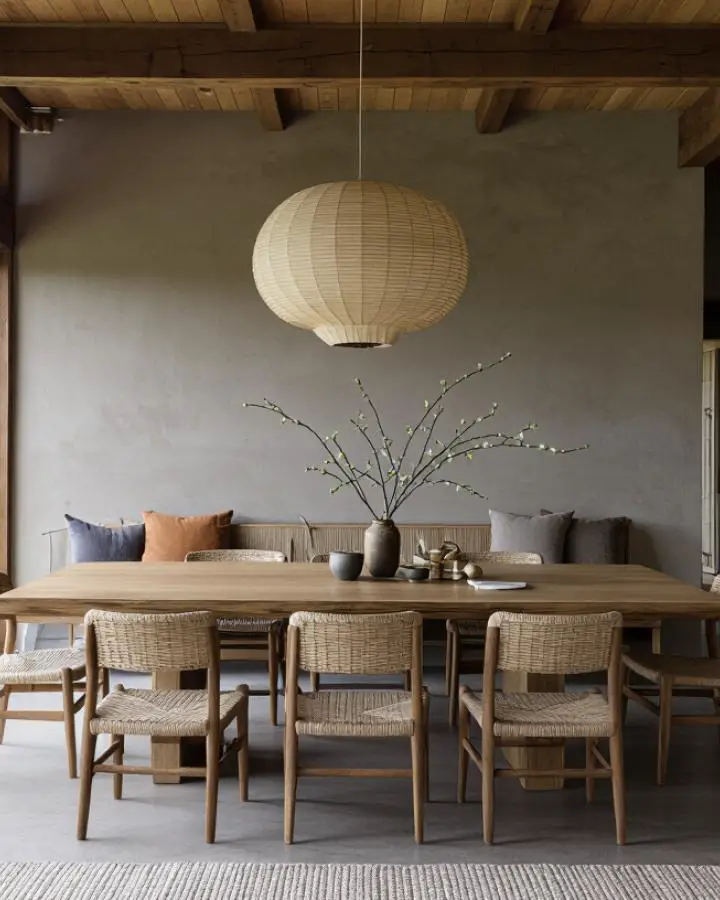 Natural woven paper lantern suspended over rustic wooden dining table with handwoven chairs.