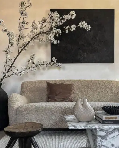 Delicate cherry blossom branches from @loft208 creating natural contrast against dark wall art and neutral furniture.