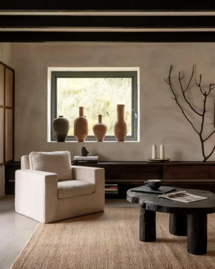 Terracotta pottery collection displayed on windowsill showcasing natural wabi sabi living room ideas. Handcrafted vessels in warm brown tones.