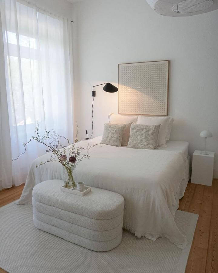 White textured cozy bedroom with boucle ottoman and sheer curtains from @cxurtniehome. Soft, inviting minimalist design.
