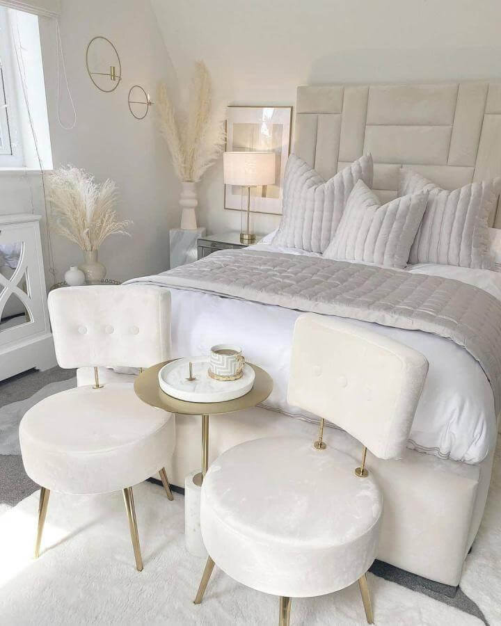 Cream velvet stools with brass legs and marble side table from @home_of_ishy. Elegant white aesthetic bedroom ideas with plush and metallic details.