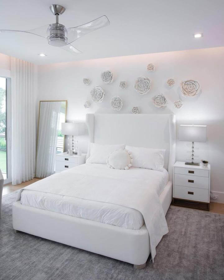 White floral wall art and sleek white leather bed in airy bedroom by @calusabaydesign with soft grey rug and crystal lamps.