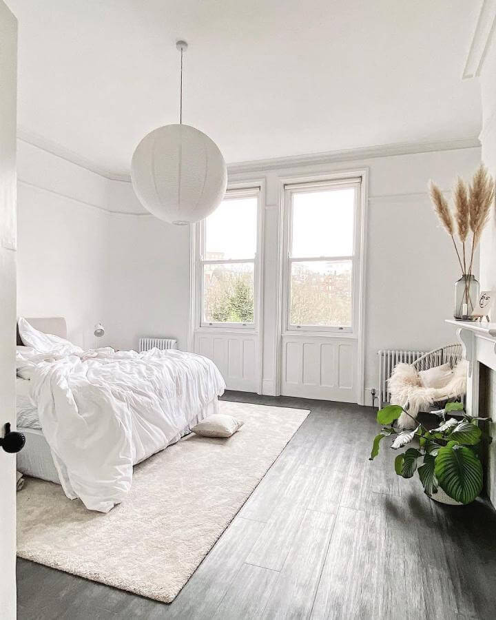 White minimalist bedroom with soft bedding, pendant light, and natural plant accents from @hearts_at_claremont. Cozy yet fresh vibe.
