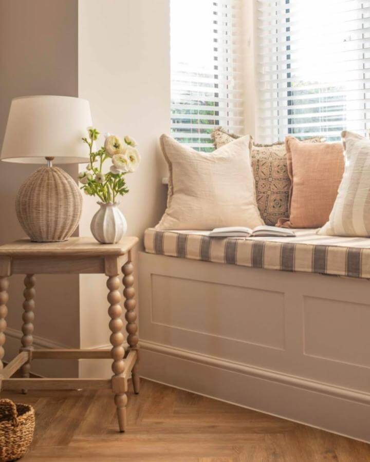 Natural light-filled cozy nook with neutral cushions and woven textures by @amandajaxninteriorphoto. Rustic wooden table and striped seat cushion.