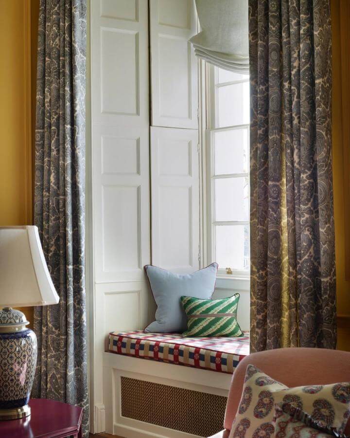 Colorful patterned cushion and pillows on a white wooden window seat with paisley drapes from @rachaelsmithphotographyltd showcasing window seat ideas.