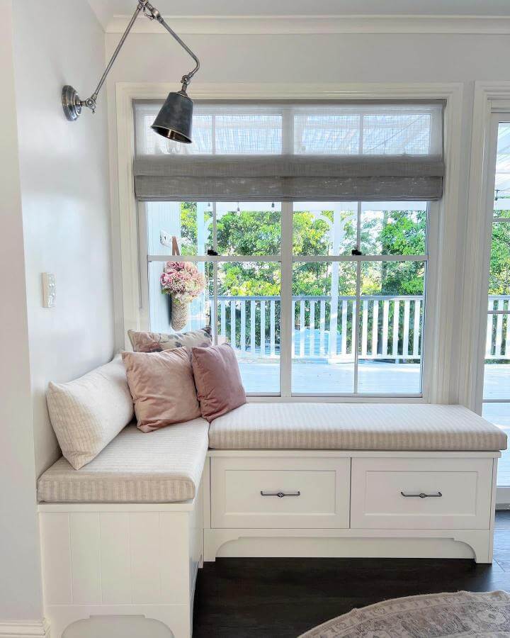 Cream and beige cushioned corner bench with storage drawers and soft lighting by @diamondcottageblooms. Cozy and practical nook.