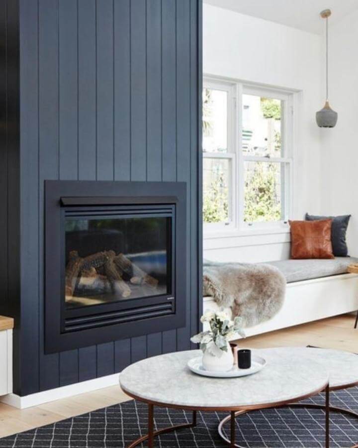 Light gray cushioned bench with brown and navy pillows near window by @appletree_designs. Cozy and stylish seating nook with natural light.