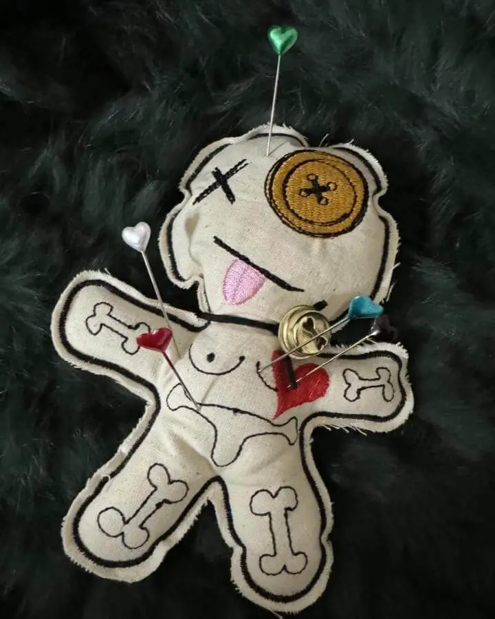 Handmade cream voodoo doll from @teawithkarin featuring colorful pins and embroidered details, perfect inspiration for witchy craft ideas.