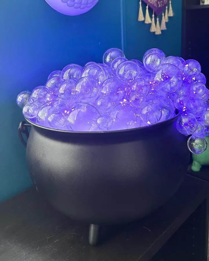 Black cauldron filled with illuminated purple bubbles from @tnoodle412. Glowing orbs overflow mystically in moody lighting.