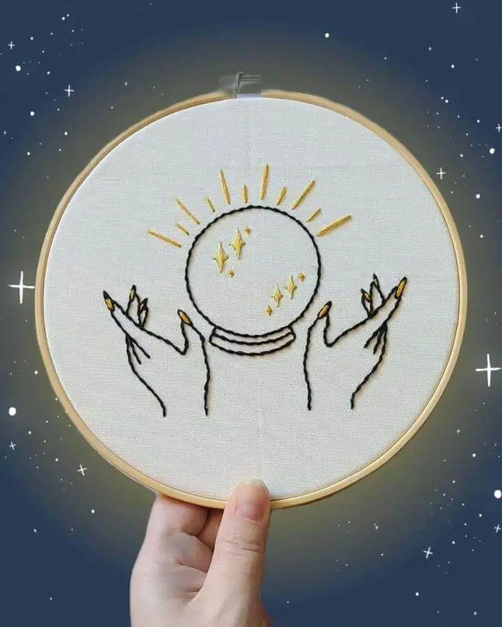 Embroidered crystal ball hoop from @streganonnastitches featuring golden sun rays and hands, perfect for witchy craft ideas and mystical home decor.