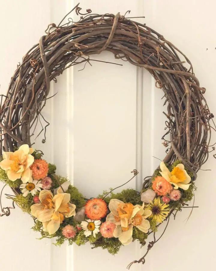 Rustic twig wreath decorated with orange pumpkins and cream flowers from @apiancreative. Perfect autumn door decoration.