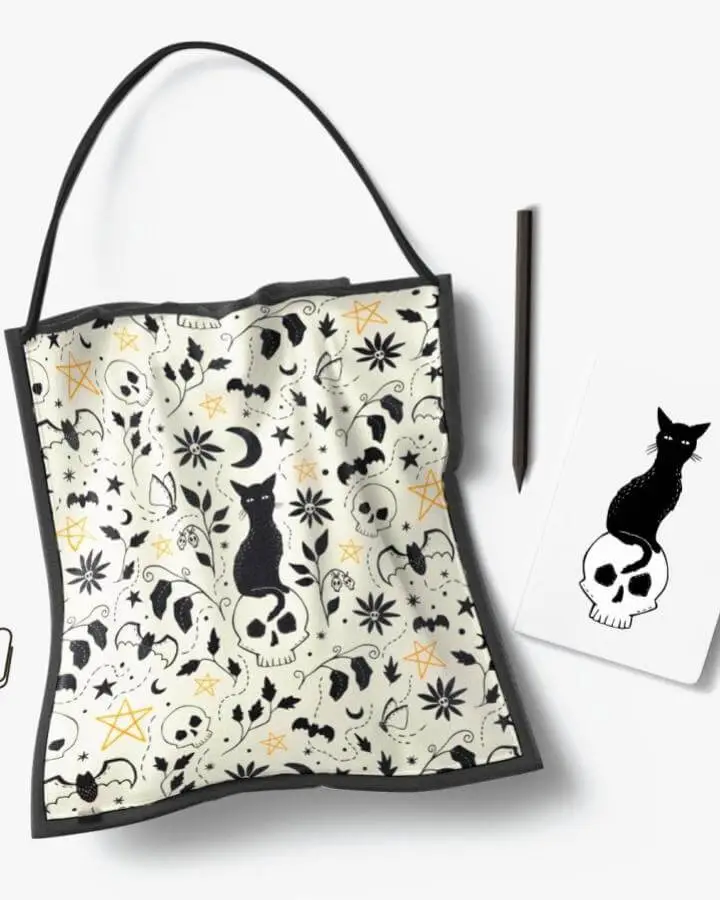 Mystical patterned tote bag and notebook from @jmhurd featuring black cats, skulls, and celestial symbols.