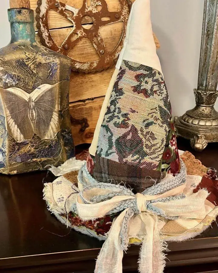 Vintage tapestry witch hat centerpiece from @thankfullyyoursllc. Handcrafted with layered fabrics and frayed cream brim details.