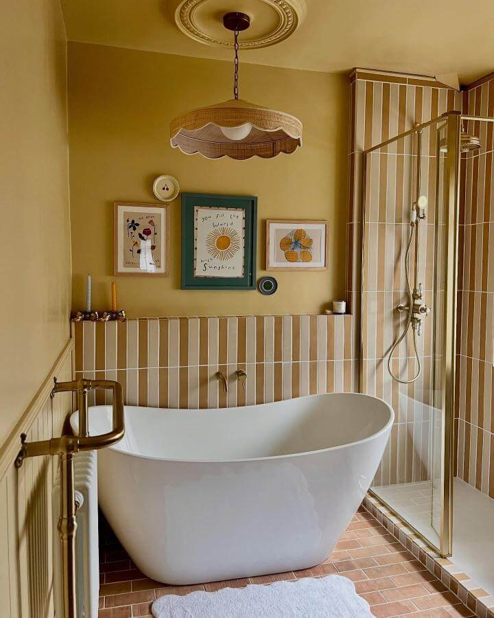 mustard yellow vertical striped tile bathroom from @homeofcharl with cozy freestanding tub and brass accents