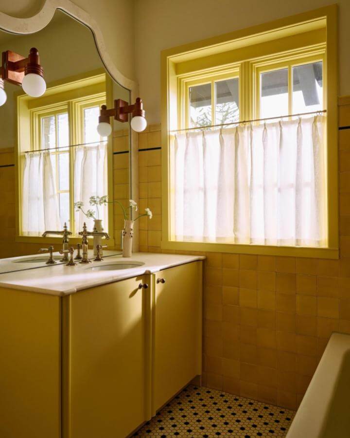 yellow bathroom ideas with sunny cabinets and vintage brass fixtures from @danielpeterphoto bright and warm space with tiled walls and soft curtain light