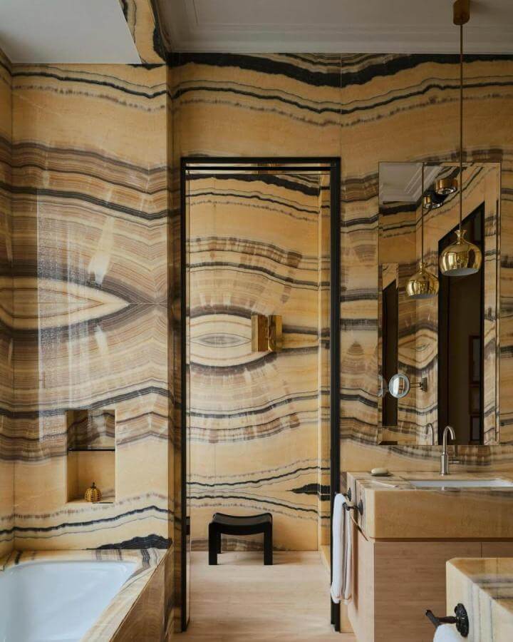 Polished yellow onyx wall bathroom from @simonpwatson with gold lights and natural stone textures for yellow bathroom ideas.