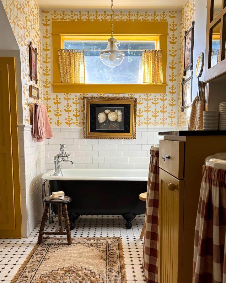 Yellow floral wallpaper bathroom with vintage clawfoot tub and gingham curtains from @ciarakenaston brightens rustic classic decor.